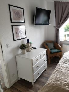 a bedroom with a white dresser and a tv on a wall at Ferienwohnung Muschelsucher in Juliusruh