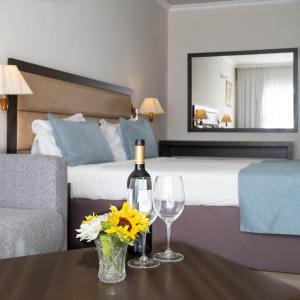a hotel room with a bed and a table with wine glasses and flowers at Kfar Maccabiah Business & Sport Hotel in Ramat Gan