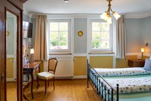 a bedroom with a bed and a desk and two windows at Pension Amthof in Oberderdingen