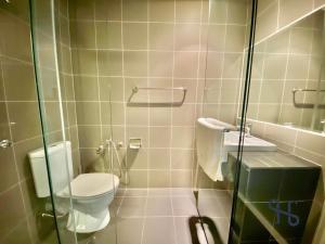 ein Badezimmer mit einem WC und einer Glasduschkabine in der Unterkunft Homesuite' Home at Aeropod SOVO in Kota Kinabalu