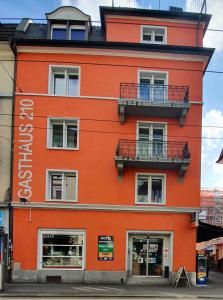 ein orangefarbenes Gebäude mit zwei Balkonen auf einer Straße in der Unterkunft Gasthaus 210 in Zürich
