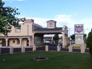 a large pink building with a sign in the grass at Knights Inn Van Horn in Van Horn