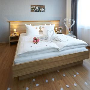 una camera da letto con un grande letto bianco con due cuori di Hotel Weimarer Berg a Apolda