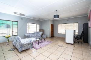 a living room with two chairs and a table at WILLOW GUEST HOUSE in Boksburg