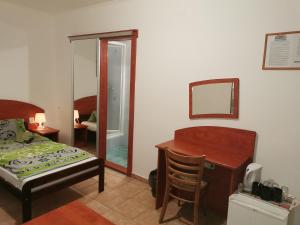a bedroom with a bed and a desk and a mirror at Penzión Rudolf in Prievidza