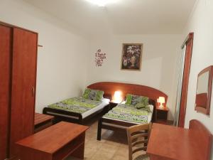 Habitación pequeña con 2 camas y mesa. en Penzión Rudolf en Prievidza