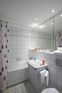 ein Badezimmer mit einer Badewanne, einem Waschbecken und einem Spiegel in der Unterkunft Hotel Weimarer Berg in Apolda