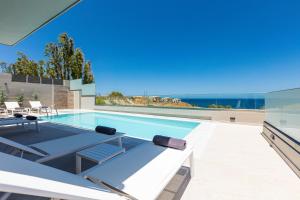 einen Pool mit Blick auf ein Haus in der Unterkunft Lagoon Seaside Villa, Sumptuous Retreat,By ThinkVilla in Panormos