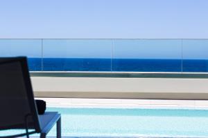 a person sitting in a chair looking out of a window at Lagoon Seaside Villa, Sumptuous Retreat,By ThinkVilla in Panormos Rethymno