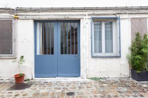 a blue front door of a white house at Beaumarchais in Paris