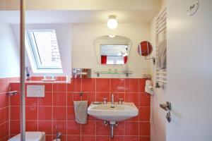 Baño de azulejos rojos con lavabo y espejo en Pension Amthof en Oberderdingen