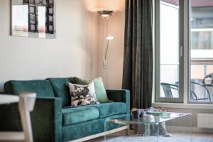 a living room with a green couch and a glass table at BJØRVIKA APARTMENTS, Teaterplassen, Oslo city center in Oslo