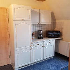 cocina con armarios blancos y microondas en Ferienwohnung Heinrich, en Kurort Altenberg