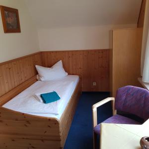 a small bedroom with a bed and a chair at Ferienwohnung Heinrich in Kurort Altenberg