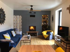 ein Wohnzimmer mit einer blauen Couch und einem Kamin in der Unterkunft Au lilas rose Maison entre campagne et village in Belvès