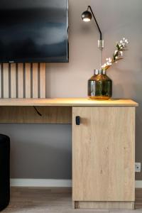 a desk with a lamp and a vase with flowers on it at BJØRVIKA APARTMENTS, Teaterplassen, Oslo city center in Oslo