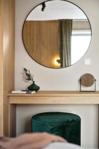 a mirror on a wall with a green chair at BJØRVIKA APARTMENTS, Teaterplassen, Oslo city center in Oslo