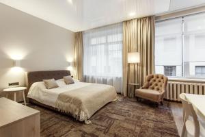um quarto com uma cama, uma cadeira e uma janela em Old Town Trio Apartments em Vilnius