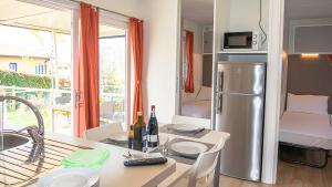 a kitchen with a refrigerator and a table with plates and wine bottles at IdeaLazise Camping and Village in Lazise