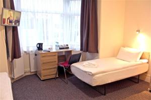 um quarto de hotel com uma cama, uma secretária e uma janela em Central Hotel Golders Green em Londres