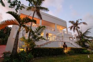 a man standing in front of a white house at Sandals Guest House in Durban