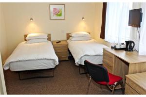 a hotel room with two beds and a red chair at Central Hotel Golders Green in London