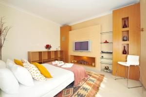 1 Schlafzimmer mit einem weißen Bett und einem TV in der Unterkunft Cosy Bedrooms Guest House in Lissabon