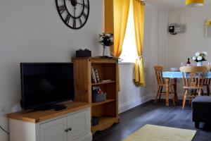 a living room with a flat screen tv on a wooden entertainment center at Woodlands View in Halesworth