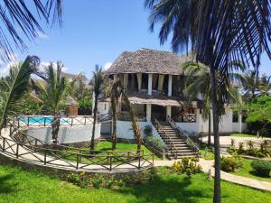 a villa with a swimming pool and palm trees at Kimya House, Watamu in Watamu