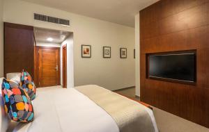 a bedroom with a bed and a television at Alreem Village Hotel in Al Jubail