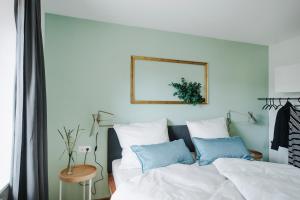um quarto com uma cama com lençóis brancos e almofadas azuis em Rotes Haus Bregenz Wald Wohnung em Bregenz