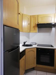 a kitchen with wooden cabinets and a black refrigerator at Appartement Le Belvédère in Roquebrune-Cap-Martin