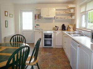 a kitchen with a table and a sink and a stove at Stone Cottage Kenmare by Trident Holiday Homes in Kenmare