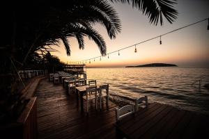 ein Dock mit Tischen und Stühlen auf dem Wasser bei Sonnenuntergang in der Unterkunft Büyükada Loc'ada in Adalar