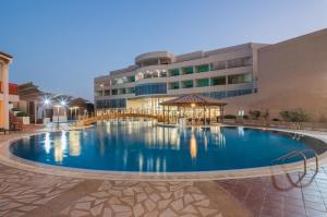 a large swimming pool in front of a large building at Alreem Village Hotel in Al Jubail