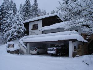 dom pokryty śniegiem z samochodami zaparkowanymi przed nim w obiekcie Gästehaus Strauss w mieście Seefeld in Tirol