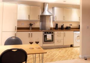 een keuken met een tafel en twee glazen wijn bij Abodebed - Handleys Court in Hemel Hempstead