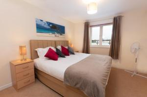 Un dormitorio con una cama con almohadas rojas y una ventana en Abodebed - Handleys Court, en Hemel Hempstead