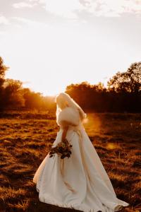 a woman in a wedding dress standing in a field at The Grosvenor Stockbridge in Stockbridge