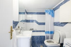a blue and white bathroom with a toilet and a sink at Casa Galini - 25m from Beach Deluxe Apartment in Kalyves