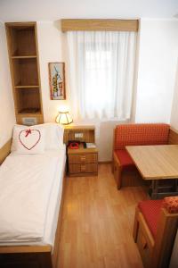プレダッツォにあるHotel Sole Family Hotelのベッド、テーブル、椅子が備わる小さな客室です。