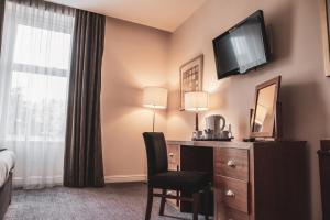 a hotel room with a desk and a television on the wall at The Angus Hotel & Spa in Blairgowrie