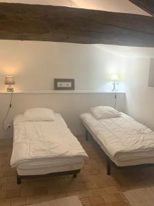 - 2 lits dans une chambre avec 2 lampes sur le mur dans l'établissement Gîte au Haras, à Les Aubiers