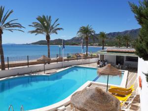 einen Pool mit Palmen und dem Meer in der Unterkunft Medplaya Hotel Vistamar Costa Dorada in Vandellòs i l’Hospitalet de l’Infant