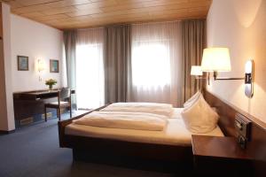 a bedroom with a bed with a desk and a window at Hotel-Restaurant Zum Kirschbaum in Rottendorf