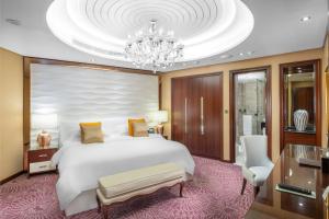 a bedroom with a large white bed and a chandelier at Al Marwa Rayhaan by Rotana - Makkah in Mecca