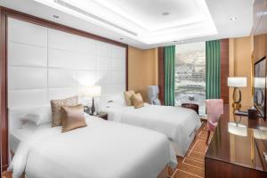 a hotel room with two beds and a window at Al Marwa Rayhaan by Rotana - Makkah in Mecca