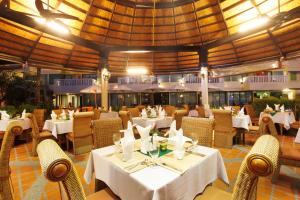 a restaurant with white tables and chairs and a large ceiling at Palmyra Patong Resort Phuket - SHA Extra Plus in Patong Beach