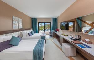 una camera d'albergo con 2 letti e una scrivania di Nuh'un Gemisi Deluxe Hotel & Spa a Vokolidha