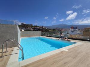 a person sitting on a ledge next to a swimming pool at DWO Nopal in Puerto de la Cruz